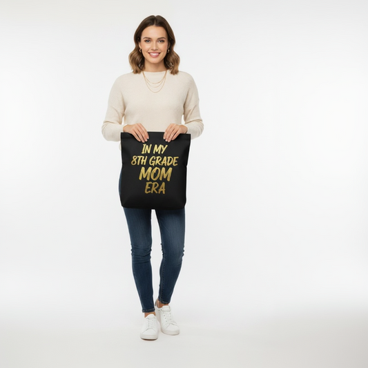 Woman holding black Class of 2027 8th Grade Mom Era tote bag for school fundraiser