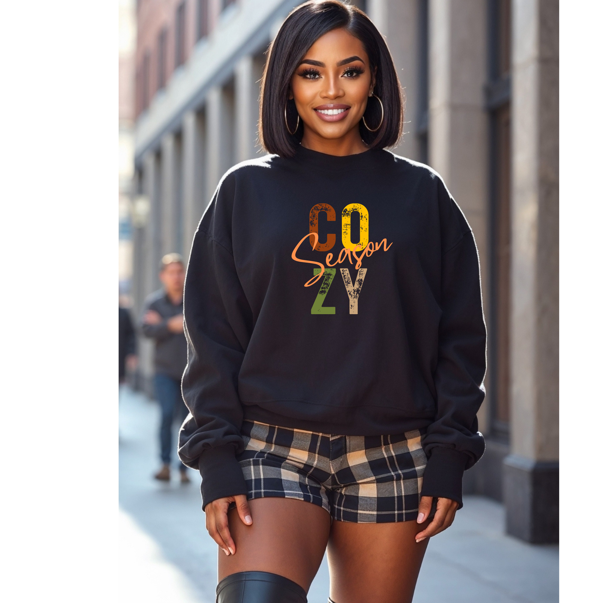 Smiling woman wearing a black “Cozy Season” sweatshirt with plaid shorts – trendy fall outfit